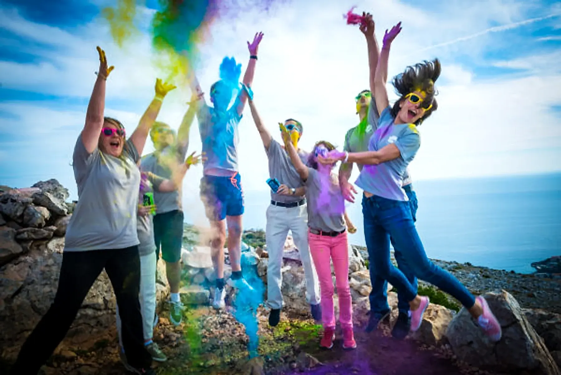 A team celebrating with colored powder on a hilltop