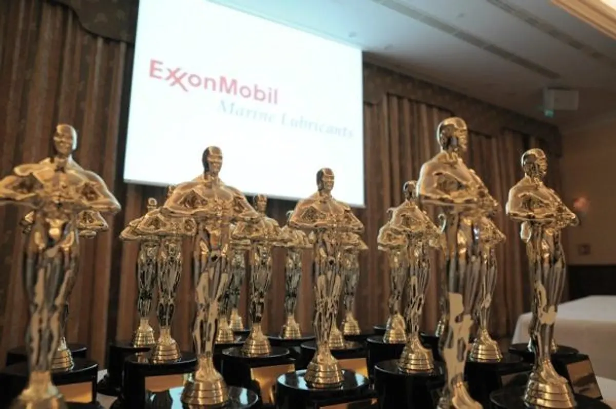 Rows of golden Oscar-style statuettes lined up on a table before a gala awards ceremony