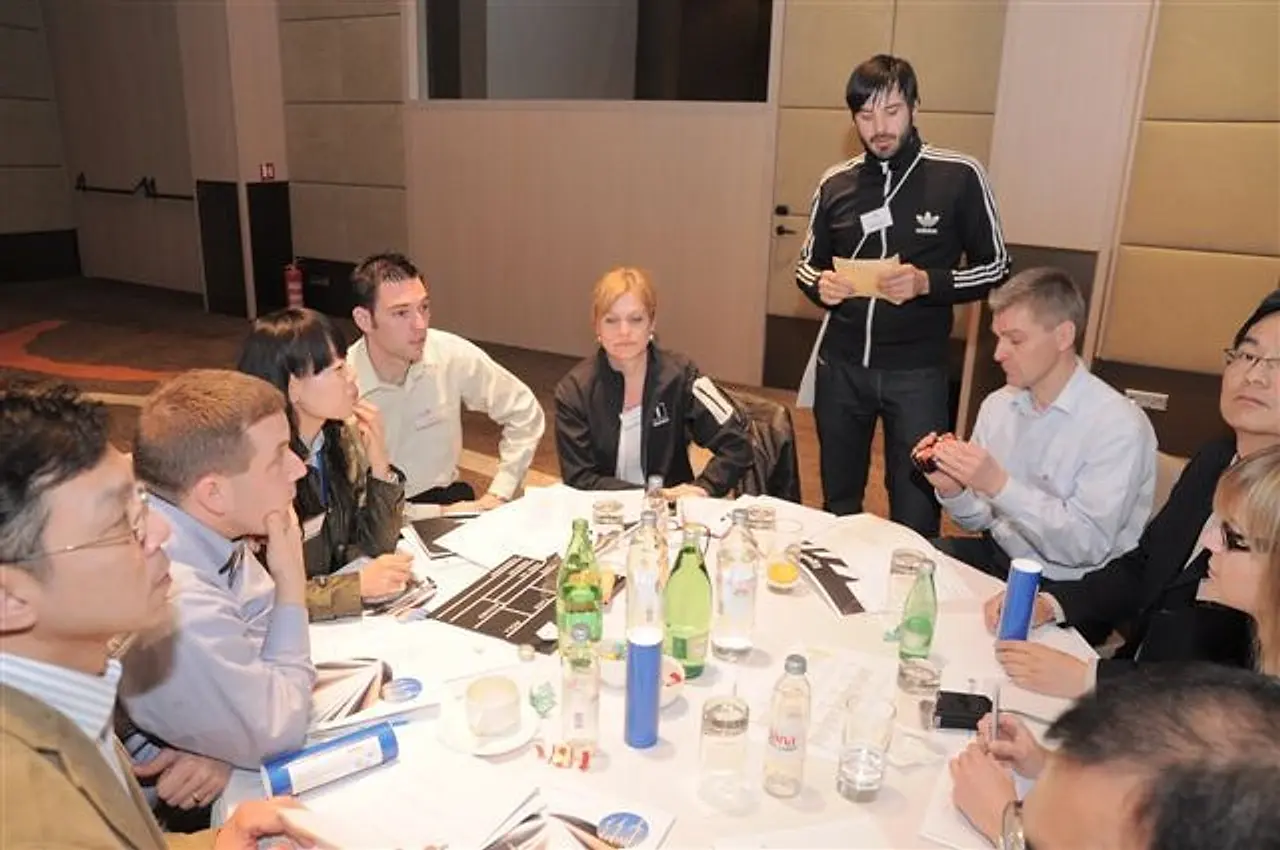 Colleagues gathered around a table during a film workshop, with a facilitator briefing the group