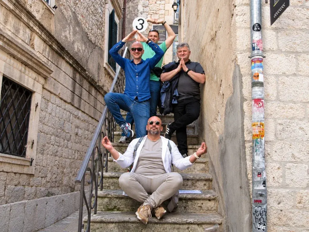 Four colleagues posing on a narrow stone staircase, one holding up a team number sign