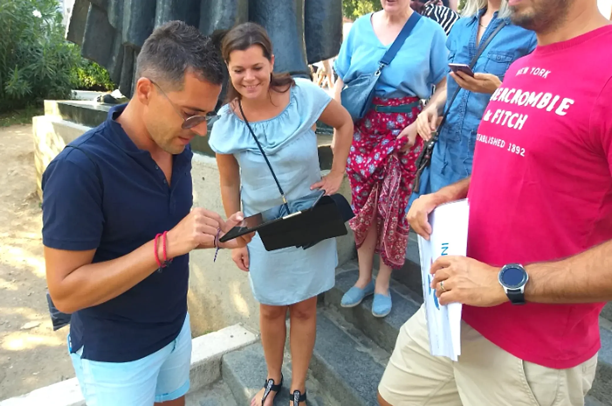 Two colleagues entering an answer on a tablet at a checkpoint while the rest of the team waits