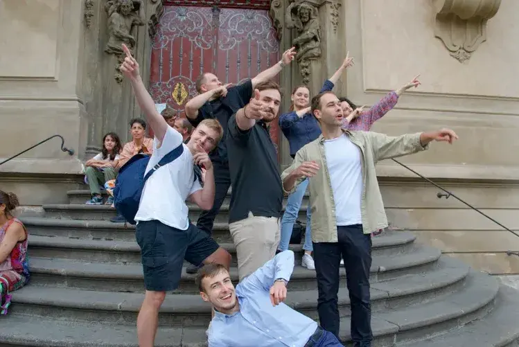 A team posing on stone steps pointing in different directions