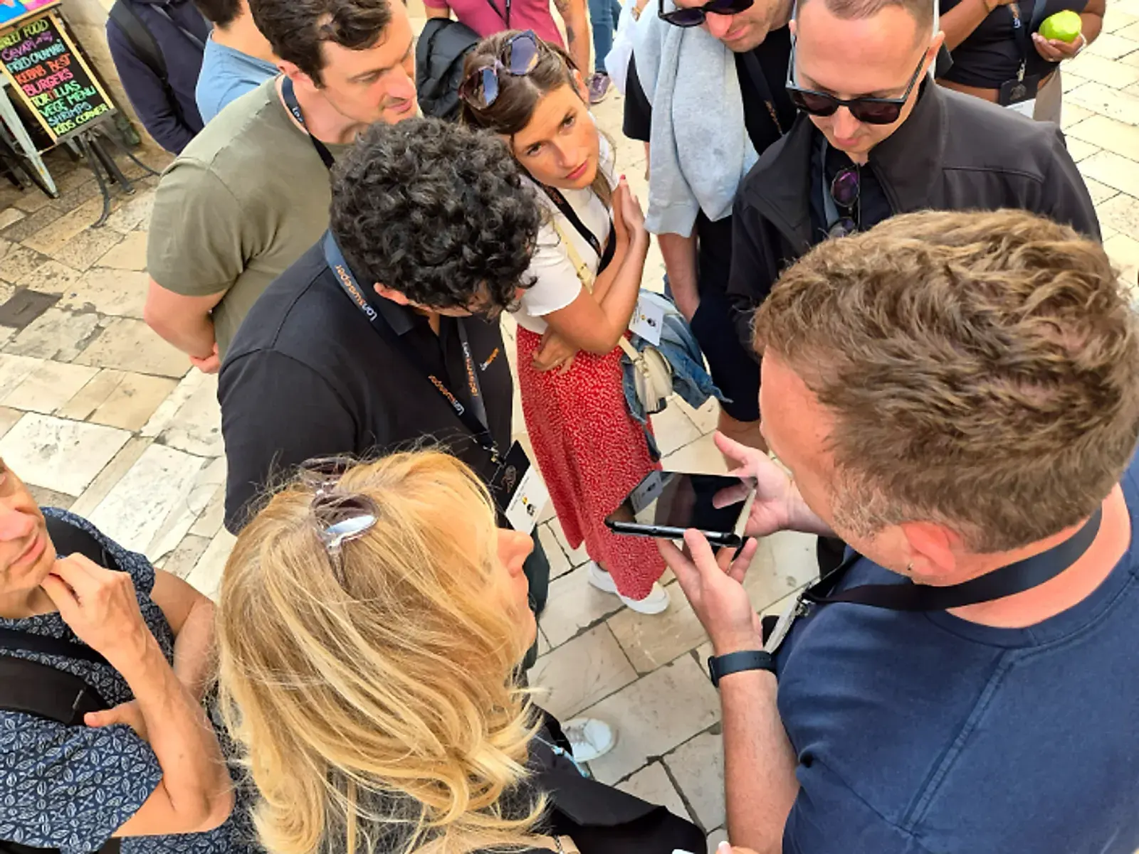 Teammates huddled around a tablet on a stone street, working out the next checkpoint